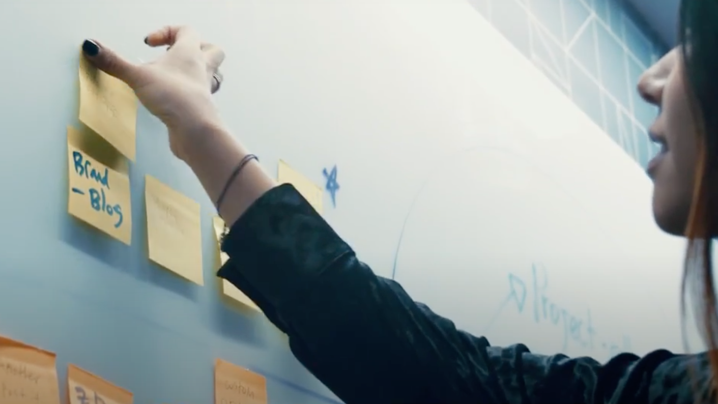 Banner with Voice123 employee sticking post-its on a whiteboard